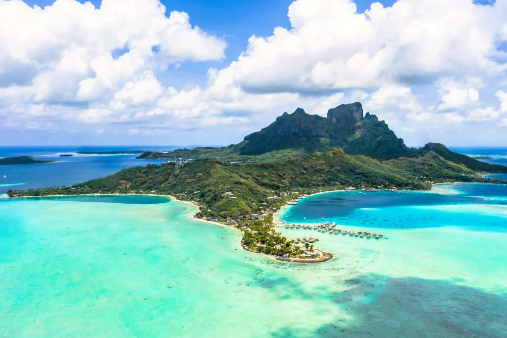 Luxury yacht anchored in Bora Bora, French Polynesia, surrounded by turquoise lagoons, overwater bungalows, and dramatic volcanic peaks.