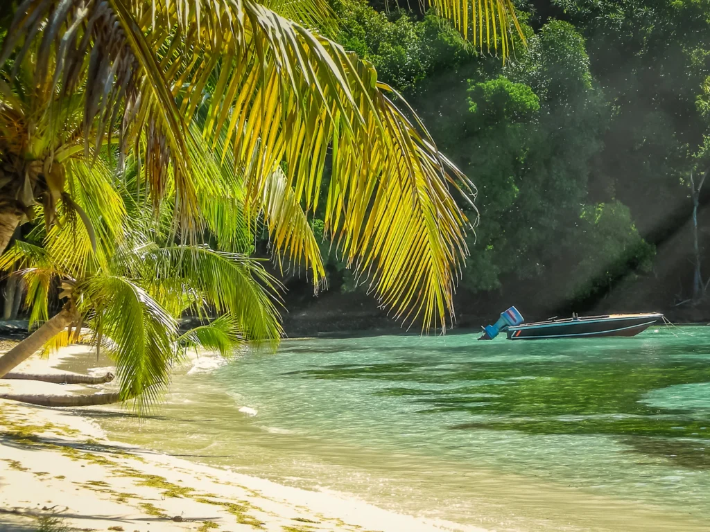 Luxury yacht anchored near Mustique in the Grenadines, with turquoise waters, lush hills, and elegant beachfront villas.