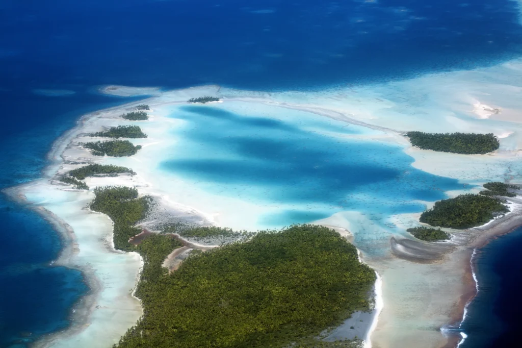 Luxury yacht anchored in Rangiroa, Tuamotus, French Polynesia, with vibrant lagoon waters, coral reefs, and lush motus surrounding the vast atoll.