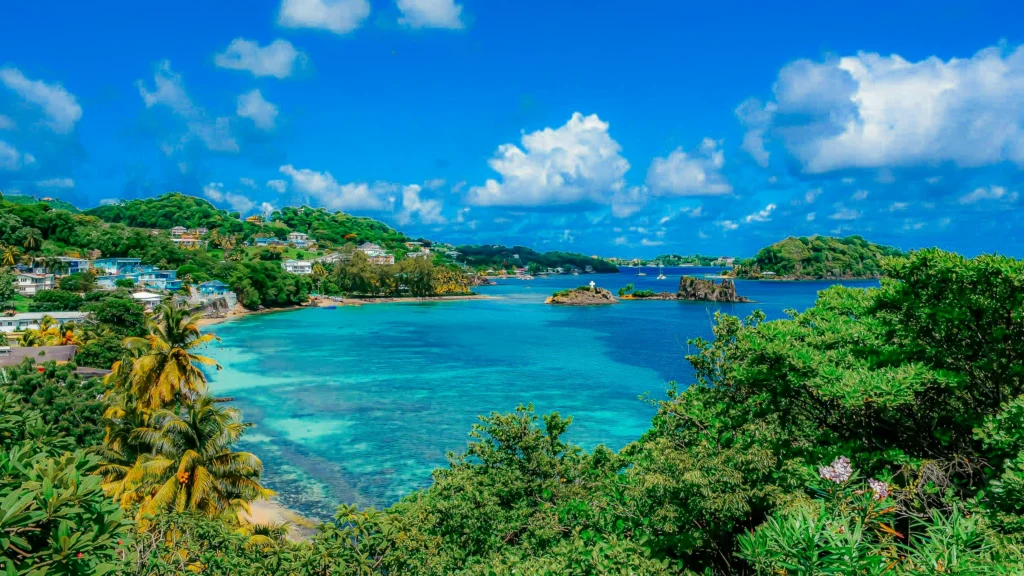 Luxury yacht anchored near St. Vincent in the Grenadines, with lush green mountains, clear Caribbean waters, and a vibrant island shoreline.