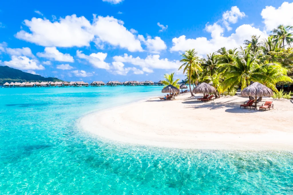 Luxury yacht anchored near Taha’a in the Society Islands, French Polynesia, with a calm lagoon, lush hills, and coral reef-lined motus.