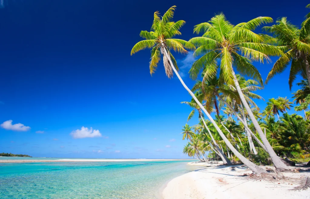 Luxury yacht anchored in Tikehau Atoll, Tuamotus, French Polynesia, with pink-sand beaches, a clear lagoon, and scattered palm-covered motus.