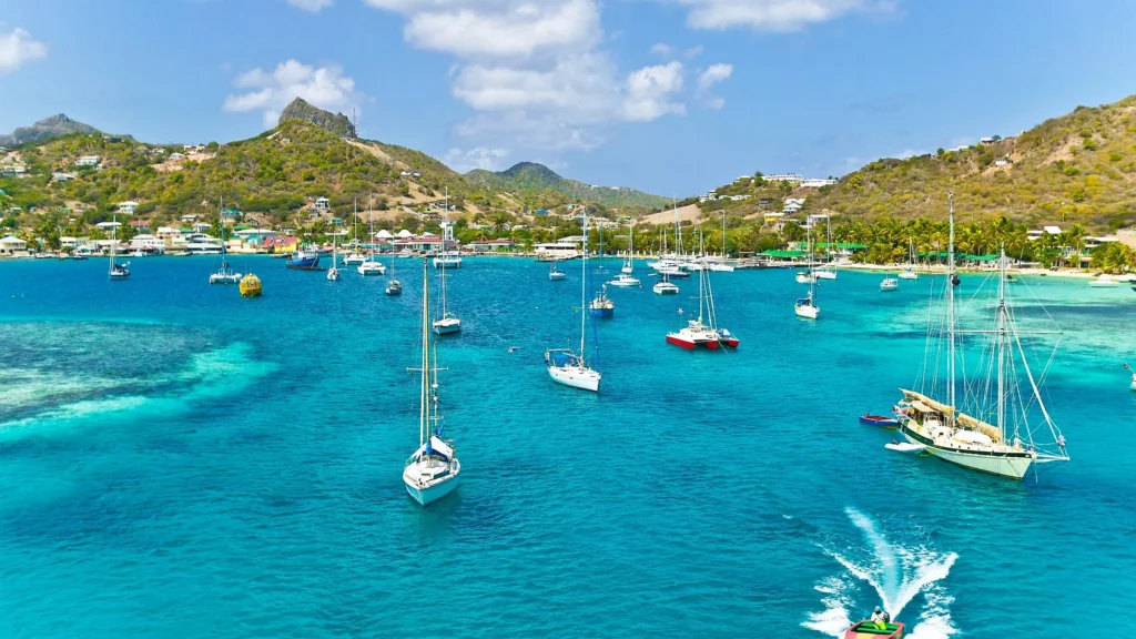 Luxury yacht anchored near Union Island in the Grenadines, with turquoise waters, palm-fringed shores, and dramatic mountainous backdrops.