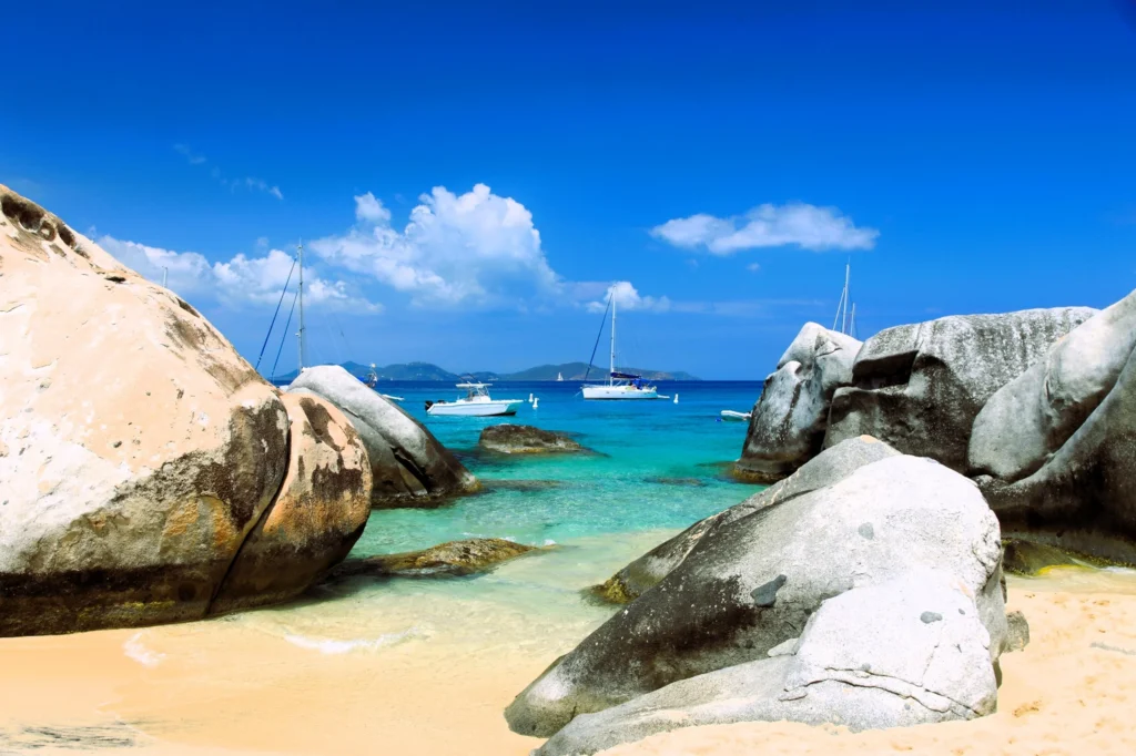 Luxury yacht anchored near Virgin Gorda in the British Virgin Islands, with turquoise waters, rocky granite boulders, and lush island scenery.