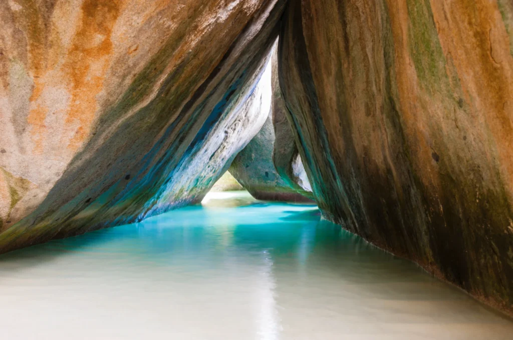 Luxury yacht anchored near Virgin Gorda in the British Virgin Islands, with turquoise waters, rocky granite boulders, and lush island scenery.