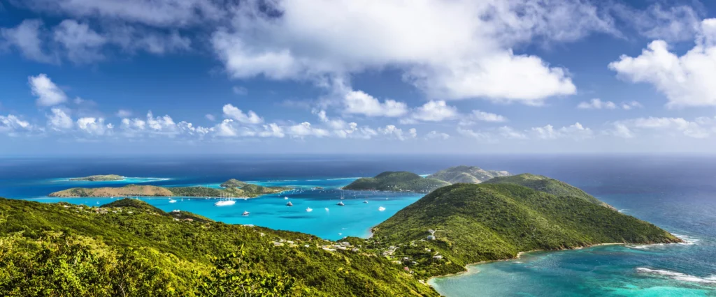 Luxury yacht anchored near Virgin Gorda in the British Virgin Islands, with turquoise waters, rocky granite boulders, and lush island scenery.