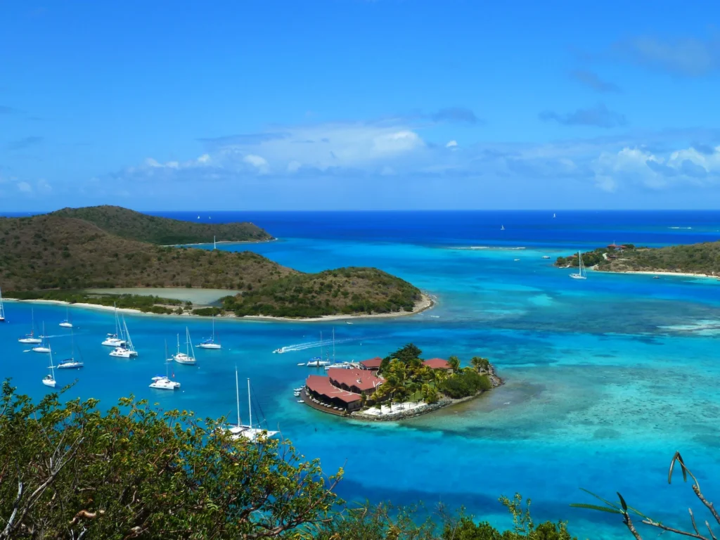 Luxury yacht anchored near Virgin Gorda in the British Virgin Islands, with turquoise waters, rocky granite boulders, and lush island scenery.